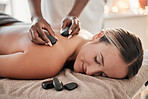 Woman, hot stone massage and therapist, hands and zen with holistic therapy and spa treatment for back. Calm, peace of mind and face, healing and stress relief with self care at wellness resort 