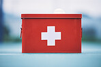 First aid, box and medical equipment for health emergency, response and treatment kit isolated in a blurred background. Red, cross and medical or medicine on a table for fast health or cure  