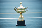 Trophy, award and target with a sports cup on an empty court outdoor for the winner, champion or victor. Gold, goal and success with a prize on the floor outside at a stadium or arena for sport