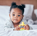 Cute, portrait and baby with a toy on her bed playing and relaxing in her modern nursery. Childhood, playful and African girl infant or newborn playing with plastic object in her bedroom at her home.