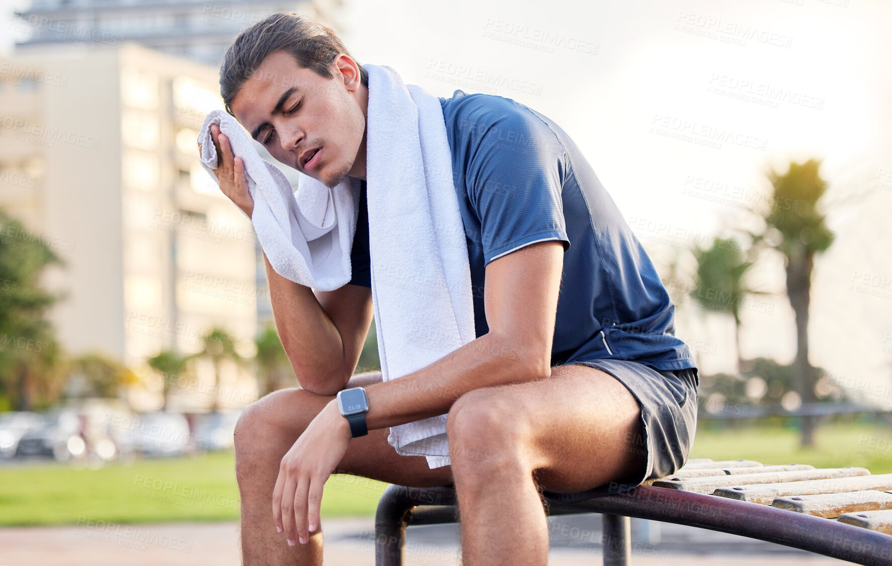 Buy stock photo Fitness, exercise and tired man with a towel on park bench to relax or rest after running for cardio. Sports person with fatigue and sweating outdoor post workout or training for health and wellness