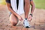 Closeup, outdoor and man with training, shoelace and workout for marathon, cardio and wellness. Zoom, male athlete and runner with sneakers, tying shoes or practice for performance, energy or balance