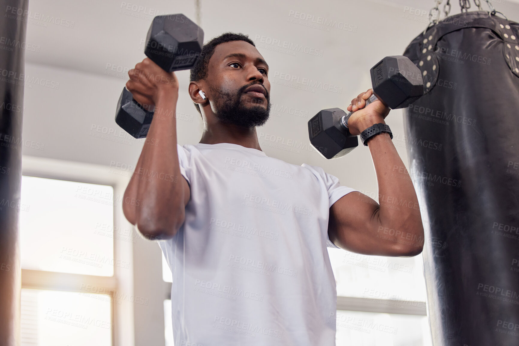 Buy stock photo Earphones, exercise music and black man with dumbbells in gym for workout, training or fitness. Sports, bodybuilder and male athlete streaming radio podcast while lifting weights for muscle strength.