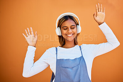 Buy stock photo Dance, happy and woman with headphones music isolated on an orange studio background. Smile, free and carefree dancing girl listening to audio, podcast or sound for entertainment and freedom