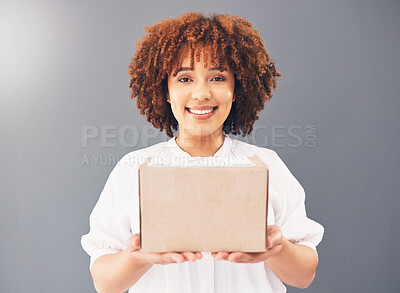 Buy stock photo Portrait, box and delivery with a black woman courier holding cardboard in studio on a gray background. Stock, supply chain and shipping with an attractive young female indoor to deliver goods
