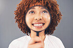 Funny, smile and black woman with a magnifying glass on face isolated on a grey studio background. Happy, comic and facial zoom of a girl with a magnifier for comedy, happiness and discovery