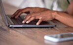 Hands, laptop and typing on wooden table for communication, email or social media. Hand of African American freelancer working remote on computer keyboard for research, browsing or networking on desk