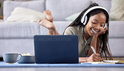 Buy stock photo Black woman, student and laptop writing in book for elearning, education or entertainment in living room at home. Happy African American female with headphones taking notes by computer lying on floor