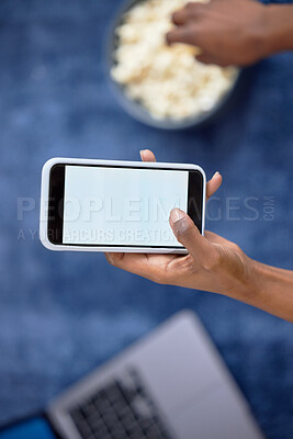 Buy stock photo Hands, phone and mockup screen above with popcorn for social media, entertainment or streaming at home. Vertical hand of person holding mobile smartphone with display for app advertising or branding