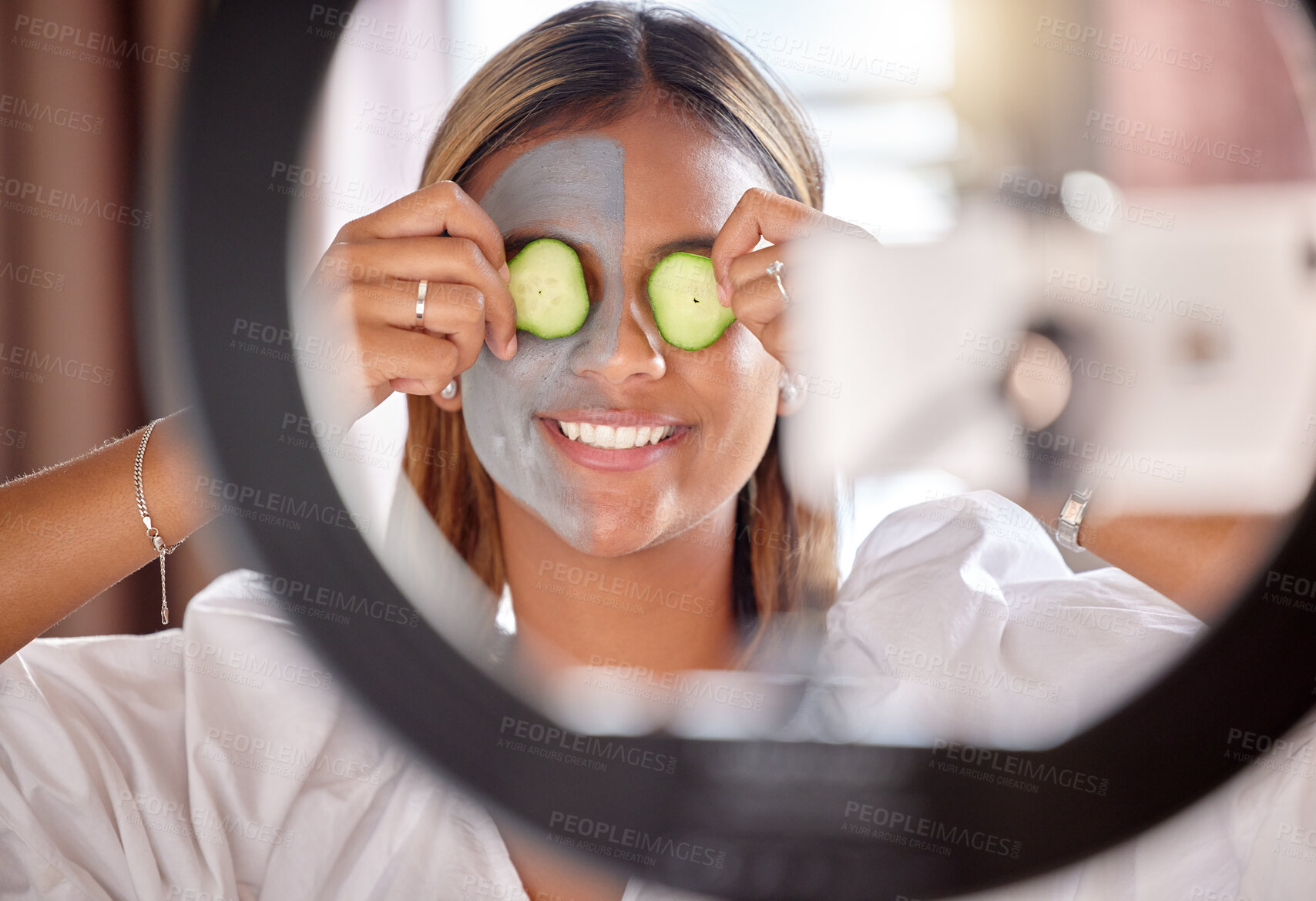 Buy stock photo Woman, vlogger and ring light of skincare influencer holding cucumber on eyes for facial wellness at home. Happy female with beauty face mask smiling for online vlog, social media post or streaming