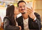 Selfie, love and kiss with a couple on a date at a restaurant together in celebration of their anniversary. Photograph, dating or kissing with a man and woman bonding or celebrating in a coffee shop