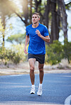 Runner, running and man training in a road outdoors for health, wellness and fitness for energy or cardio strength. Athlete, healthy and person exercise or workout in the street for a challenge