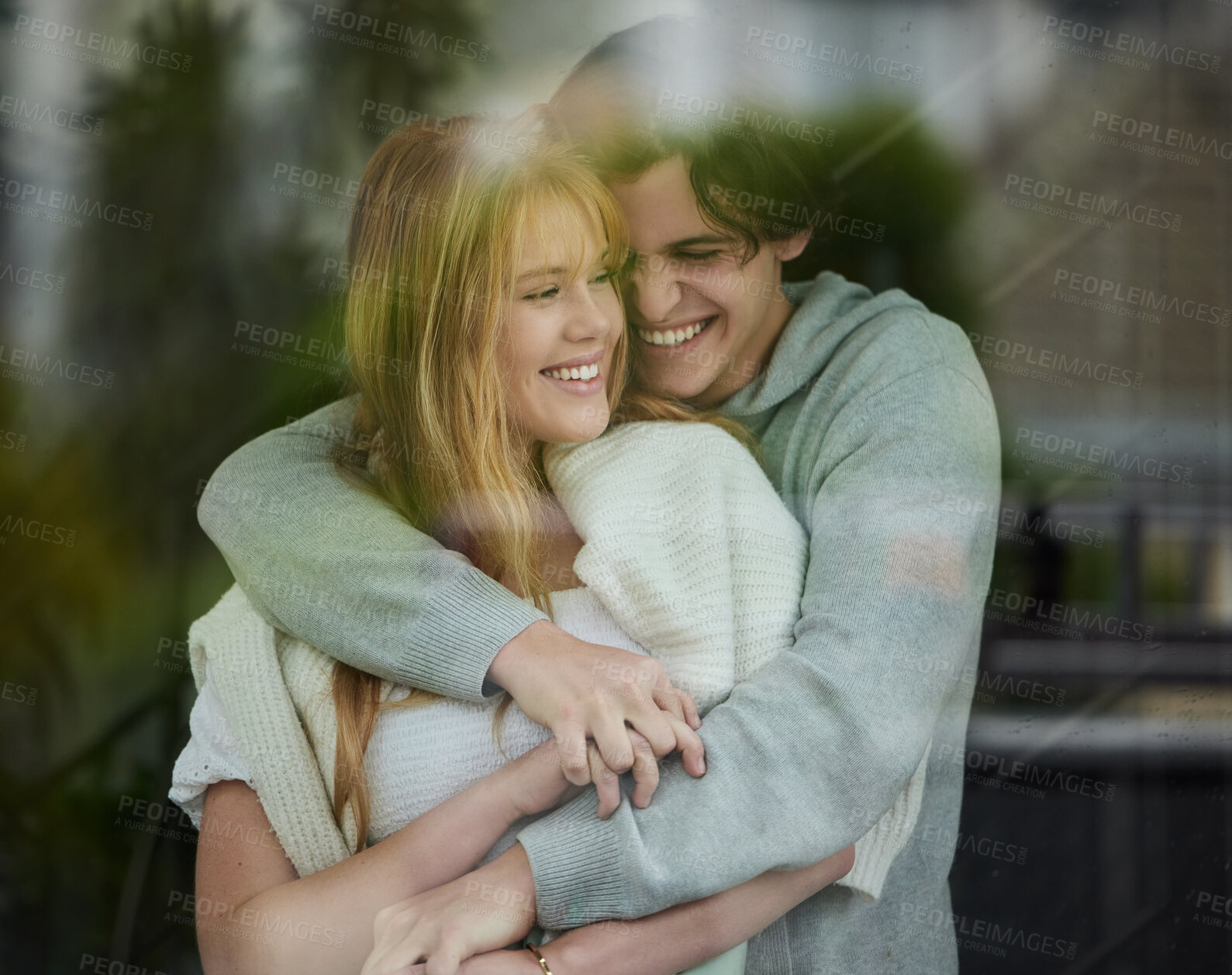 Buy stock photo Couple hug, happiness with smile by window and love with young people, partnership and holding hands with trust. Commitment, relationship and care with happy man and woman are content with joy