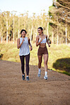 Women, running and fitness outdoor in nature for workout or exercise together for health and wellness. People friends on trail for morning cardio, training and talking while happy about sports body