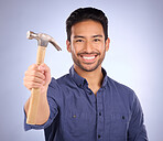 Construction, showing and portrait of an Asian man with a hammer isolated on a studio background. Building, happy and builder with a tool for repairs, maintenance and handyman work on a backdrop