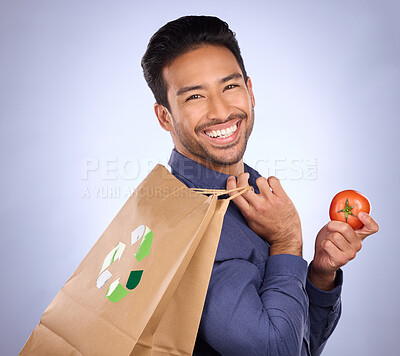 Buy stock photo Man in portrait, happy and recycling paper bag with tomato and sustainable shopping on studio background. Eco friendly, vegetable and climate change awareness in retail, sustainability and health