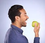 Man, face and profile, eating apple with nutrition, food and health, diet and fruit in hand on studio background. Healthy lifestyle, wellness and detox to lose weight, organic and vegan with fibre 