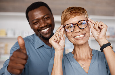 Buy stock photo Thumbs up, optometry and woman with glasses for vision or wellness in optics store. Healthcare portrait, hand emoji or smile of happy elderly female with black man or optometrist with success gesture