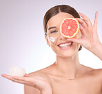 Woman, face and grapefruit with moisturizer for skincare nutrition, cream or healthy diet against gray studio background. Portrait of female with fruit and creme for natural organic facial cosmetics