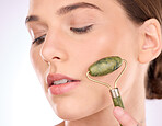 Woman, face and hand with roller for skincare beauty, cosmetics or facial treatment against a gray studio background. Female with rolling tool for cosmetic anti aging, dermatology or skin wellness