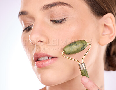 Buy stock photo Woman, face and hand with roller for skincare beauty, cosmetics or facial treatment against a gray studio background. Female with rolling tool for cosmetic anti aging, dermatology or skin wellness
