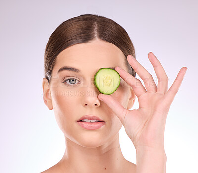 Buy stock photo Woman, face and hand with cucumber for skincare nutrition or healthy diet against a gray studio background. Portrait of female holding vegetable for organic facial treatment or natural cosmetics