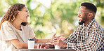 Coffee date, black couple and happy outdoor talking and bonding at table. Man and woman with a drink or tea to relax with communication to talk about love and care at cafe or shop for conversation