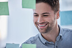 Creative man, writing and smile for schedule planning on glass board for brainstorming tasks at office. Happy male smiling in project plan, post it or sticky note for company strategy or startup