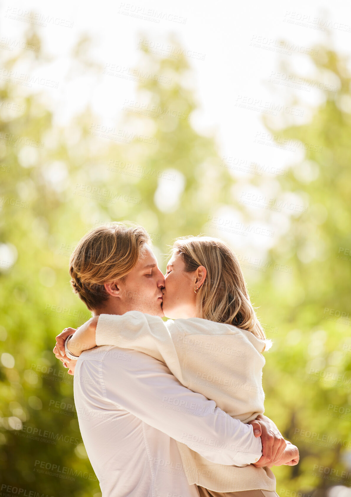 Buy stock photo Nature, love and couple kiss for happy, quality time and bonding on weekend, vacation and holiday together. Dating, relationship and young mana nd woman hugging, kissing and romantic embrace in park