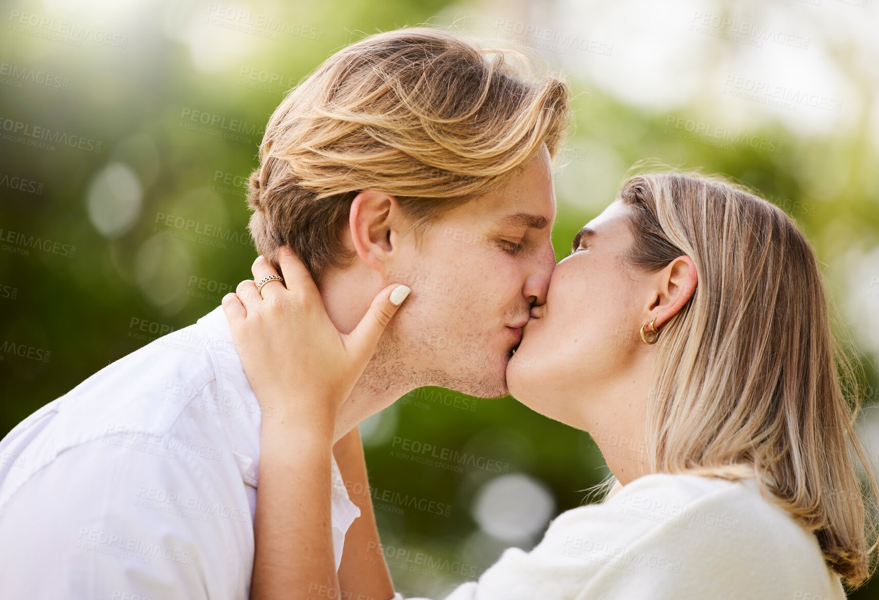 Buy stock photo Park, love and couple kiss for romance, quality time and bonding for engagement, vacation and holiday together. Dating, happy and young man and woman hugging, kissing and romantic embrace in nature