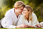 Love, grass and park with a couple lying together on a field for romance or affection during a date. Spring, nature or peace with a young male and female bonding while enjoying a summer picnic