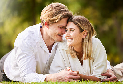 Buy stock photo Love, grass and park with a couple lying together on a field for romance or affection during a date. Spring, nature or peace with a young male and female bonding while enjoying a summer picnic