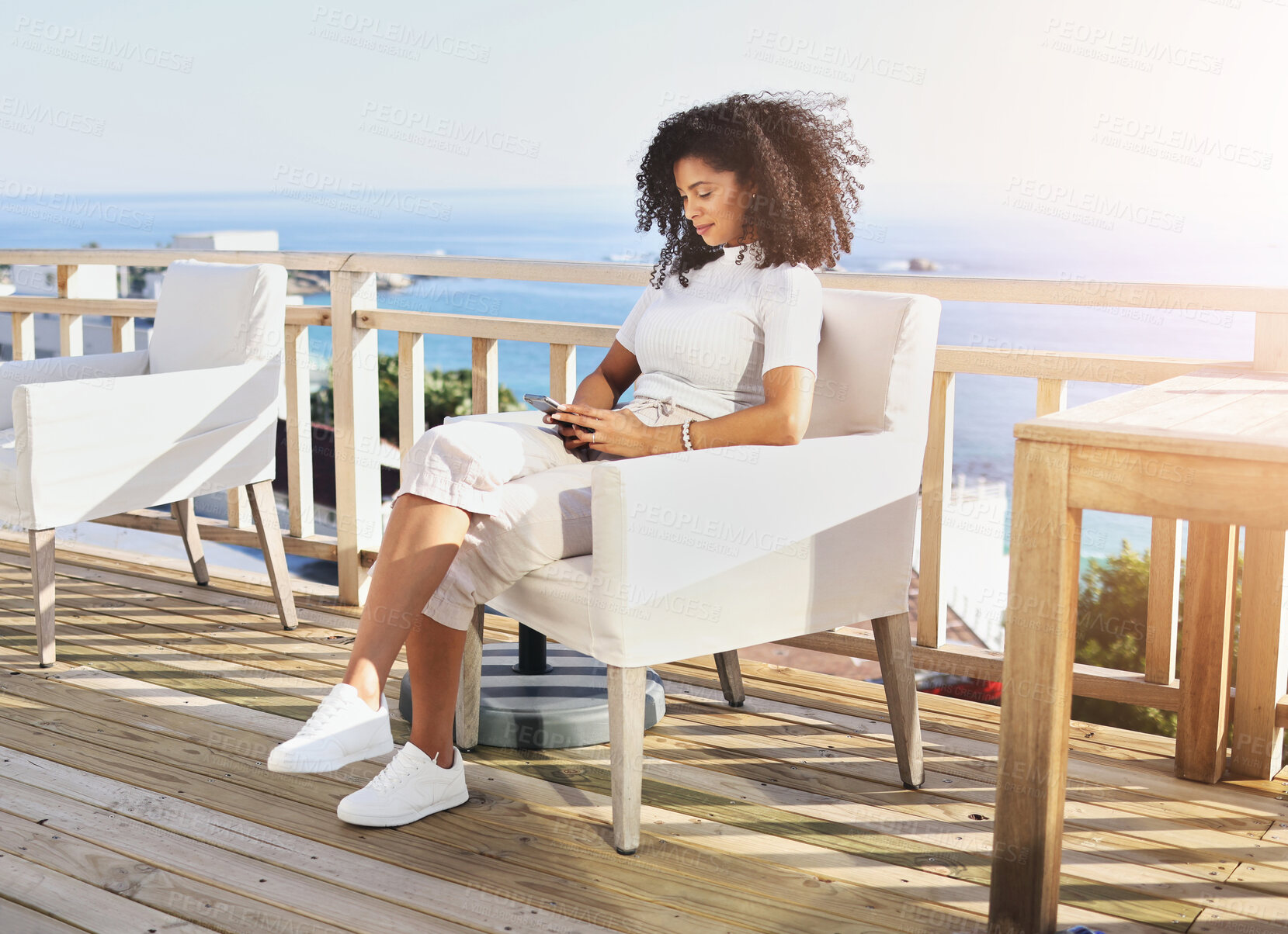 Buy stock photo Phone, balcony and woman relax at restaurant, holiday house or vacation hotel for luxury lifestyle by seaside. Black person typing on cellphone or smartphone for travel blog update and chat in summer