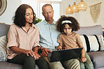 Girl watching a movie on laptop with her grandparents while relaxing on sofa in the living room. Technology, rest and child streaming video or film with grandfather and grandmother for entertainment.