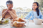 Family, food and grandmother with girl a table for lunch, part or social gathering on a patio. Love, dinner and senior woman laughing with grandchild while sharing a meal, happy and smile outdoors