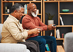 Gaming, fun and senior black man friends playing a video game together in the living room of a home. Sofa, funny or retirement with a mature male gamer and friend enjoying a house visit to game
