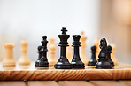 Chess, board games and black pieces on wooden table in focus with queen protecting the king in strategic match. Vintage game in problem solving for skilled players in tactics or strategy on mockup