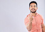 Angry, rude and portrait of an Asian man with a middle finger isolated on a grey studio background. Mockup, space and Japanese guy with a mean, bad and negative hand gesture for anger and aggression