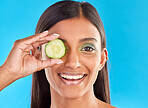 Skincare, beauty and portrait of Indian woman with cucumber, makeup and facial detox with smile on blue background. Health, wellness and sustainability, organic luxury cleaning and grooming cosmetics