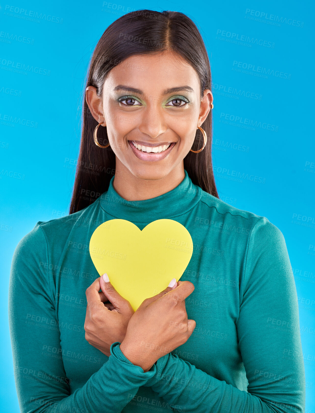 Buy stock photo Portrait, makeup and heart on valentines day with a woman in studio on a blue background for love or health. Face, beauty and romance with an attractive young female holding a cut out emoji or symbol