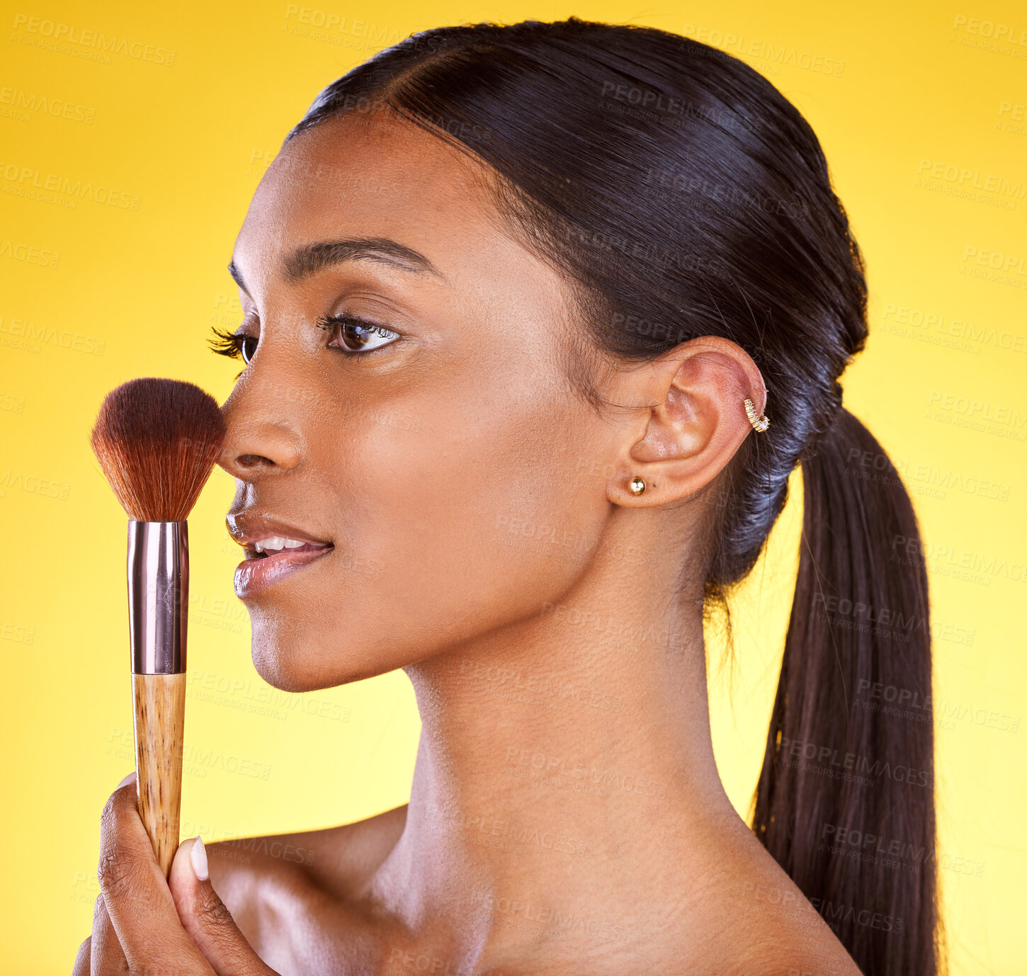 Buy stock photo Beauty, makeup and brush with indian woman in studio for cosmetics, foundation or product. Cosmetology, application and glow with girl model for self care, powder and tool in yellow background studio