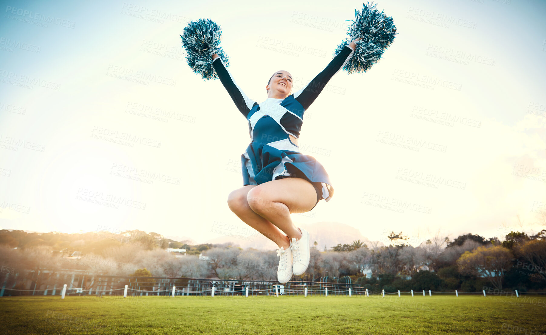 Buy stock photo Sports woman, sky and cheerleader jump with energy to celebrate goal outdoor. Cheerleading or athlete person dance in nature with pompoms for performance, game or competition on a green grass field