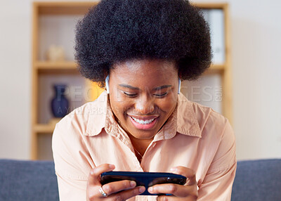 Woman playing a mobile game on her phone in landscape mode in the lounge at home. Excited young gamer smiling and laughing while enjoying some fun online entertainment in leisure with gaming apps