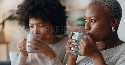 Chocolate drink and black woman friends on sofa talking and having winter celebration. African people or gen z women enjoying sweet milk coffee or cocoa beverage on couch in their apartment lounge