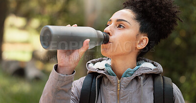 Hiking woman drinking water in nature, forest and mountain park for healthy lifestyle, wellness and outdoor adventure. Young black girl, water bottle and trekking, freedom and walk in morning woods