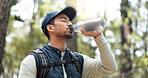 Water, drink and man with fitness hiking, exercise and thirsty in forest, nature and woods. Motivation, health and training with man hydrate after hike in nature environment for health, and wellness