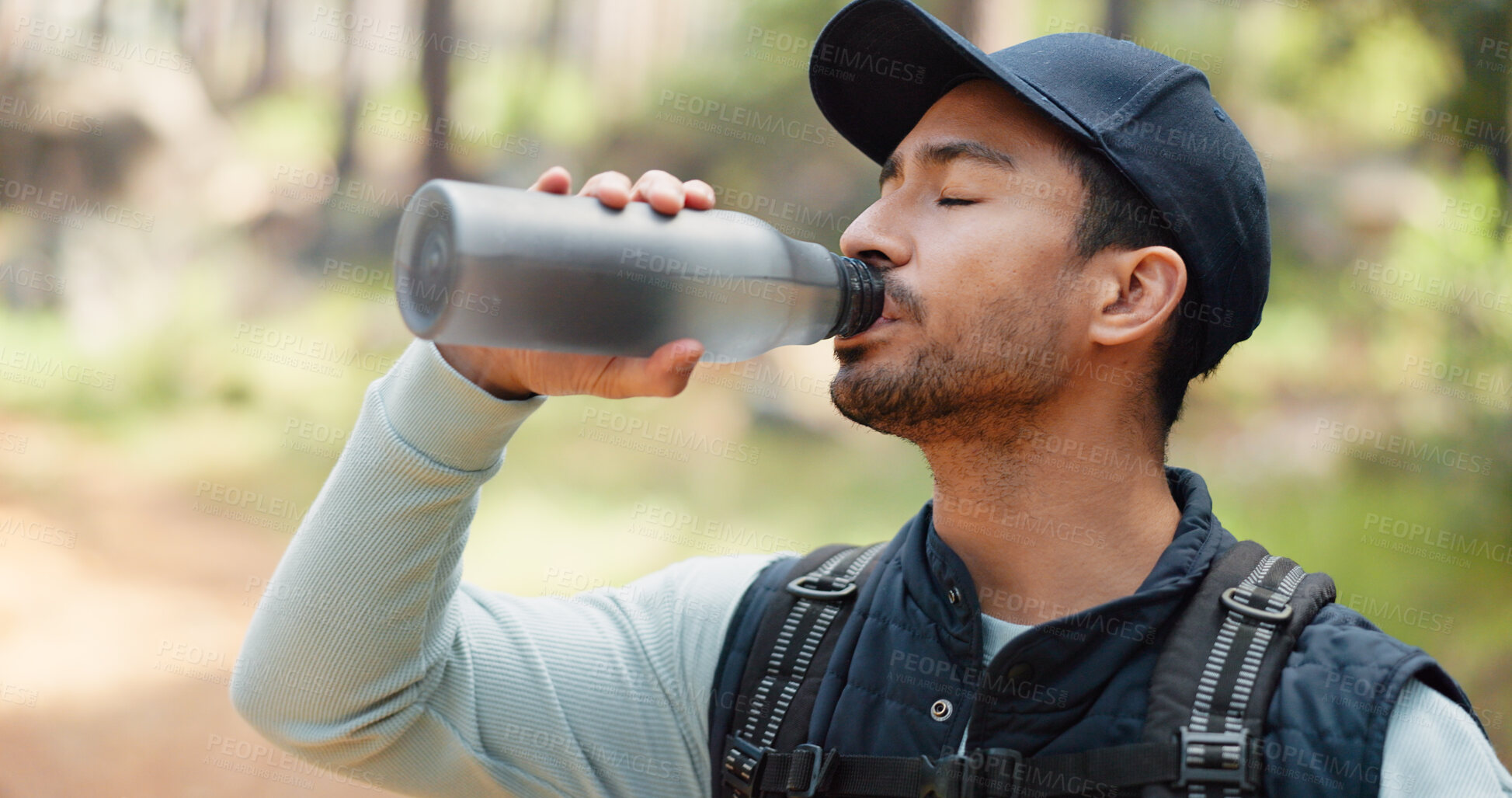 Buy stock photo Hiking, forest and man drinking water in nature, park or woods for outdoor fitness, health and training. Young person with liquid bottle for nutrition, tired and exercise break for travel or trekking