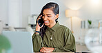 Happy business woman talking on phone call or young entrepreneur answering cellphone while sitting in front of work laptop in an office. Indian female executive smiling and laughing at a funny joke.