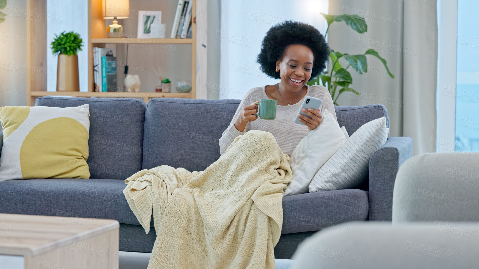 Buy stock photo Coffee, phone and happy black woman on sofa in home living room, social media and reading news. Drink tea, smartphone and African person on couch in blanket, relax and typing email on internet app.