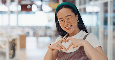 Happy woman, heart and love for creative fashion style in a office with a smile and happiness with hands for support of announcement. Portrait of asian employee with emoji sign for marketing project